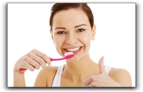 woman brushing her teeth giving a thumbs up
