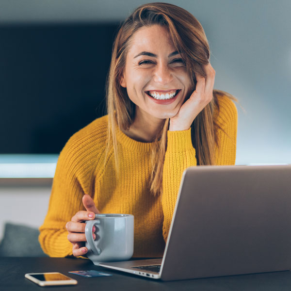 woman in yellow sweater working on laptop