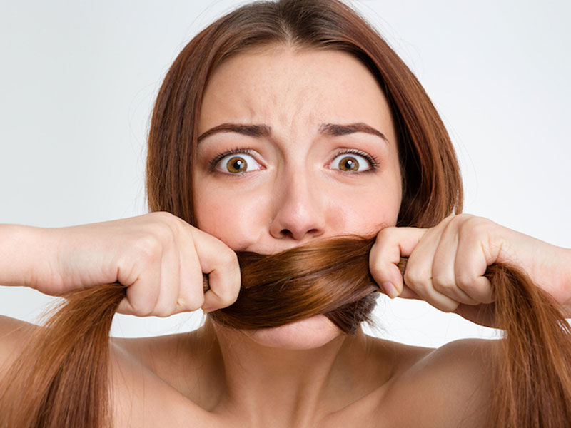 a girl hiding her teeth with hairs