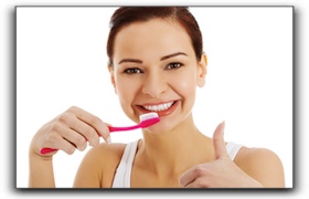 woman brushing her teeth giving a thumbs up